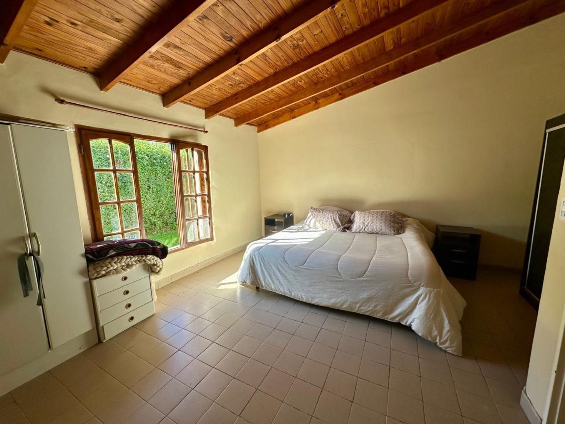 Dormitorio con techo de madera y ventana